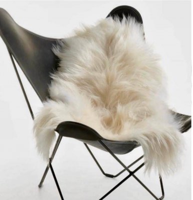 Vitt långhårigt fårskinn 100 cm placerat i soffa som inredningsdetalj